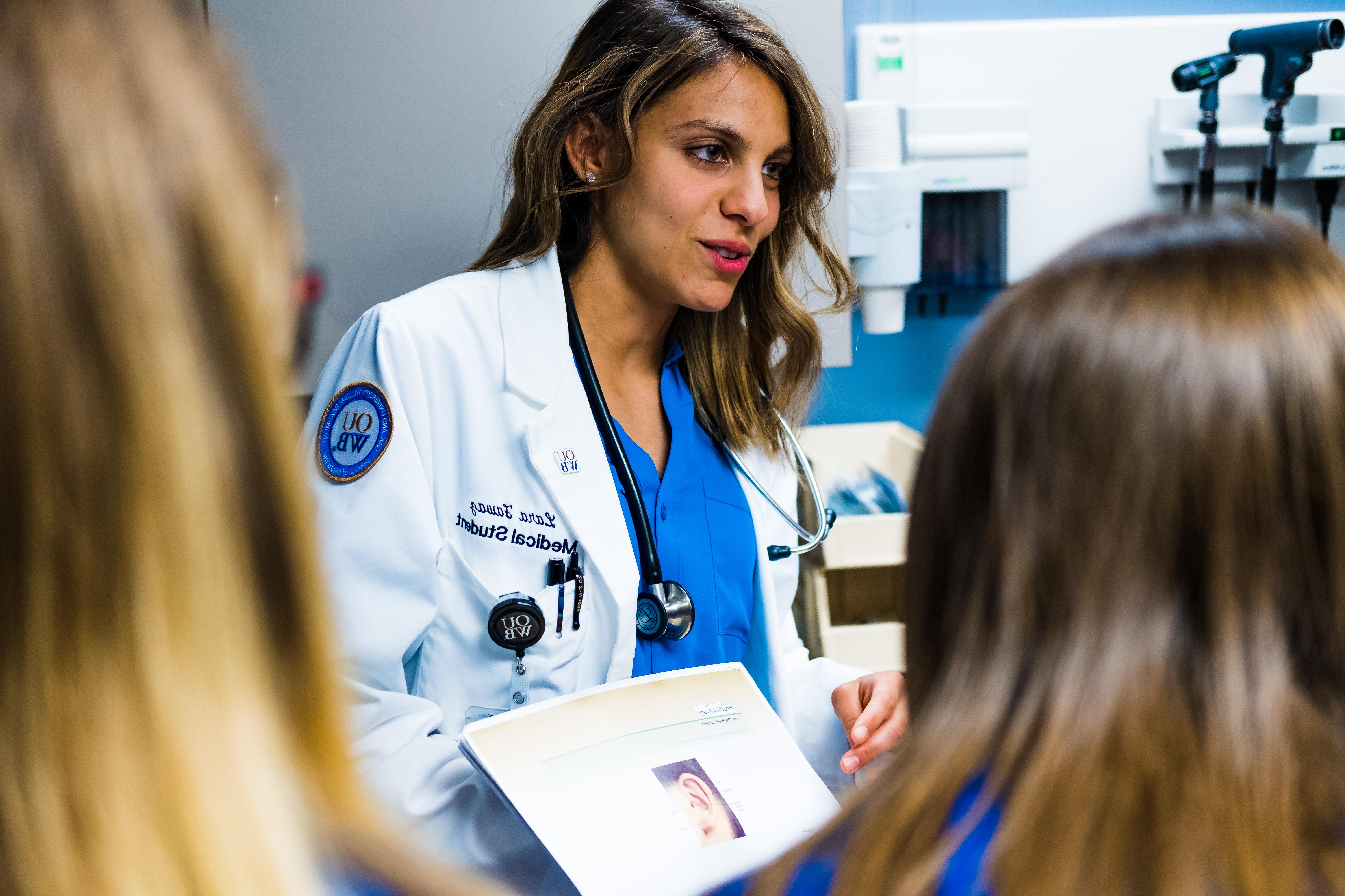 A medical student shows and explains a medical photo to high school students.